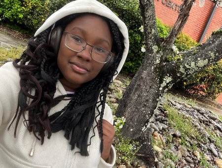 Student wearing glasses, headphones and a hoodie outside